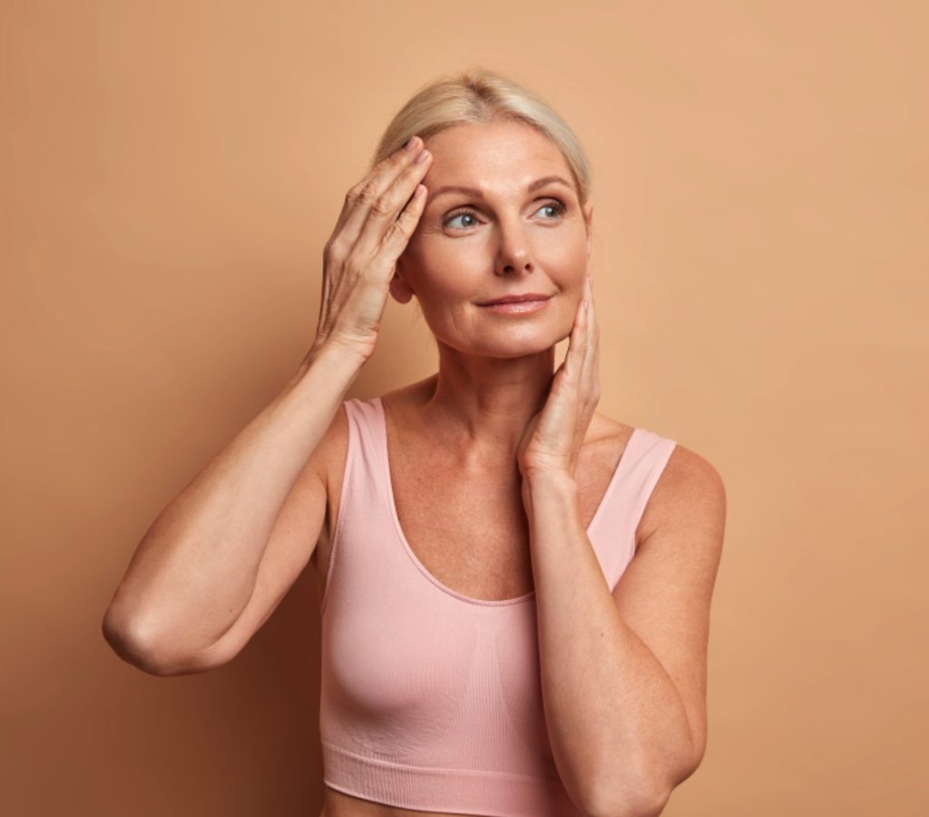 Mature woman touching her face after non-surgical facelift treatment at Vive Medical Spa in Tijuana