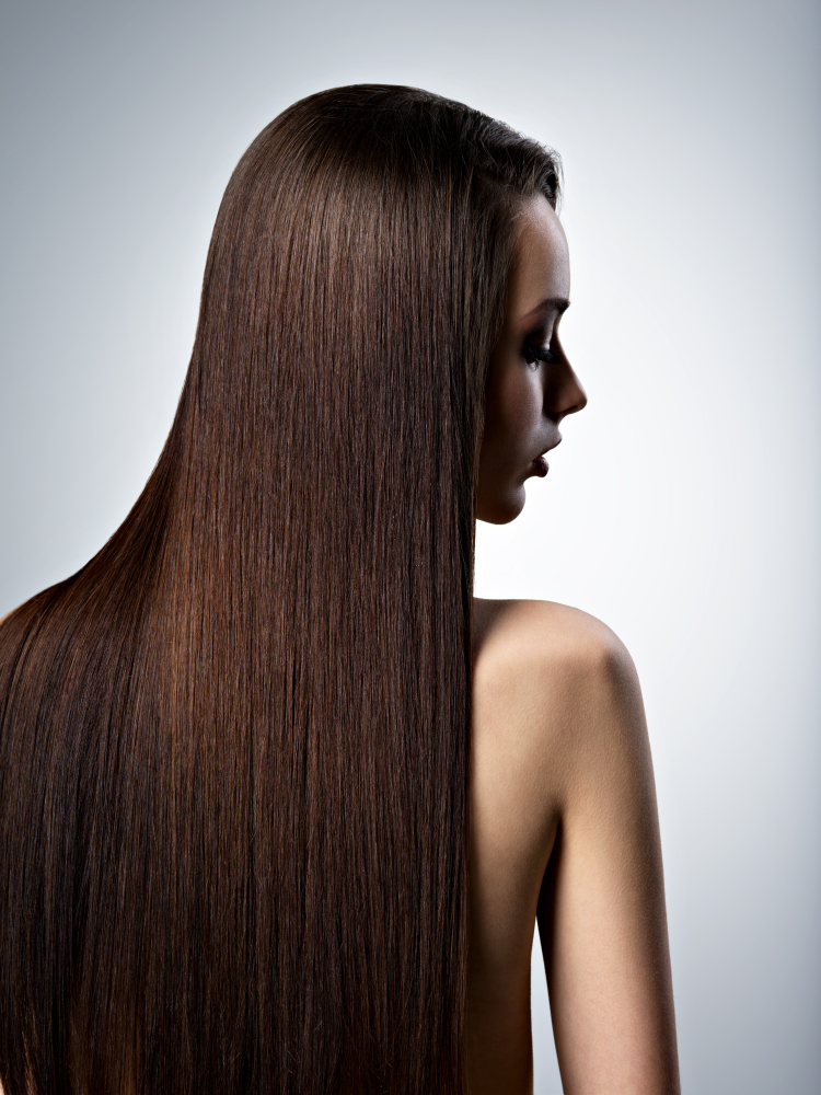 Woman with long straight healthy brown hair showcasing hair restoration and aesthetic treatments